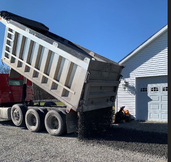 Truck spreading crusher run on a driveway.